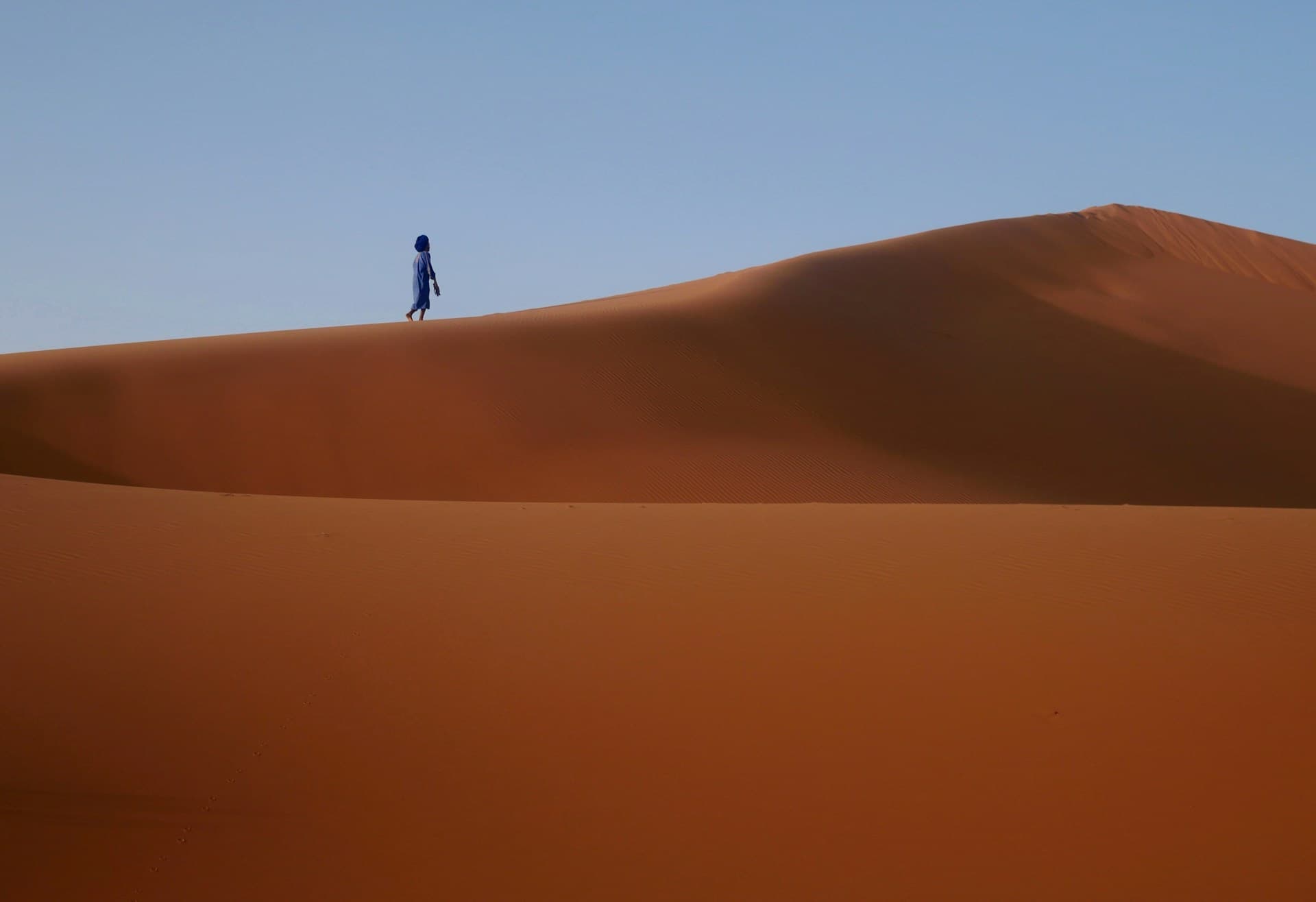 A man walking in the Moroccan desert.